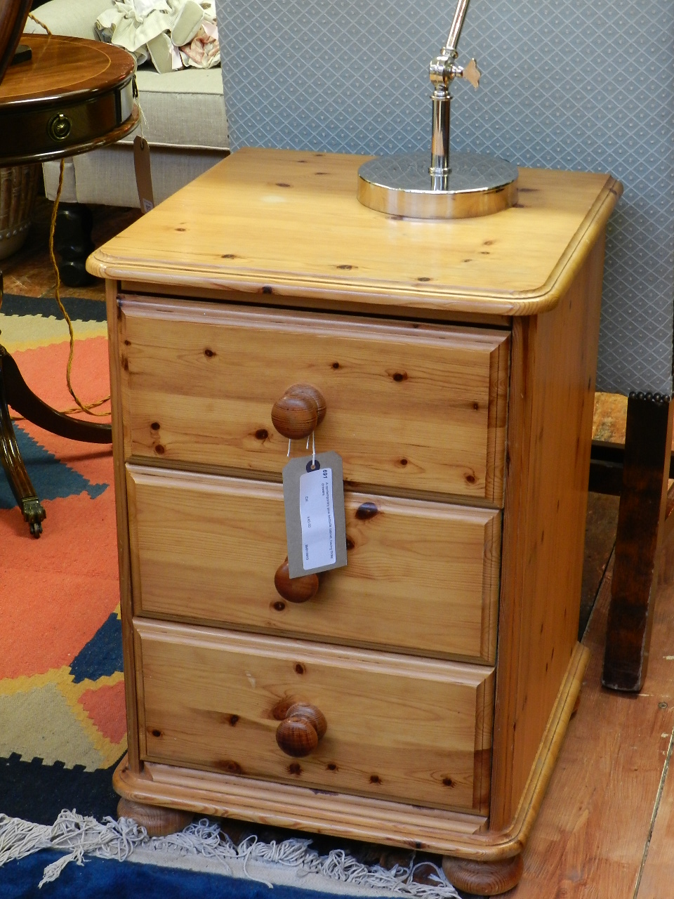 A contemporary pine bedside cabinet, having three drawers.