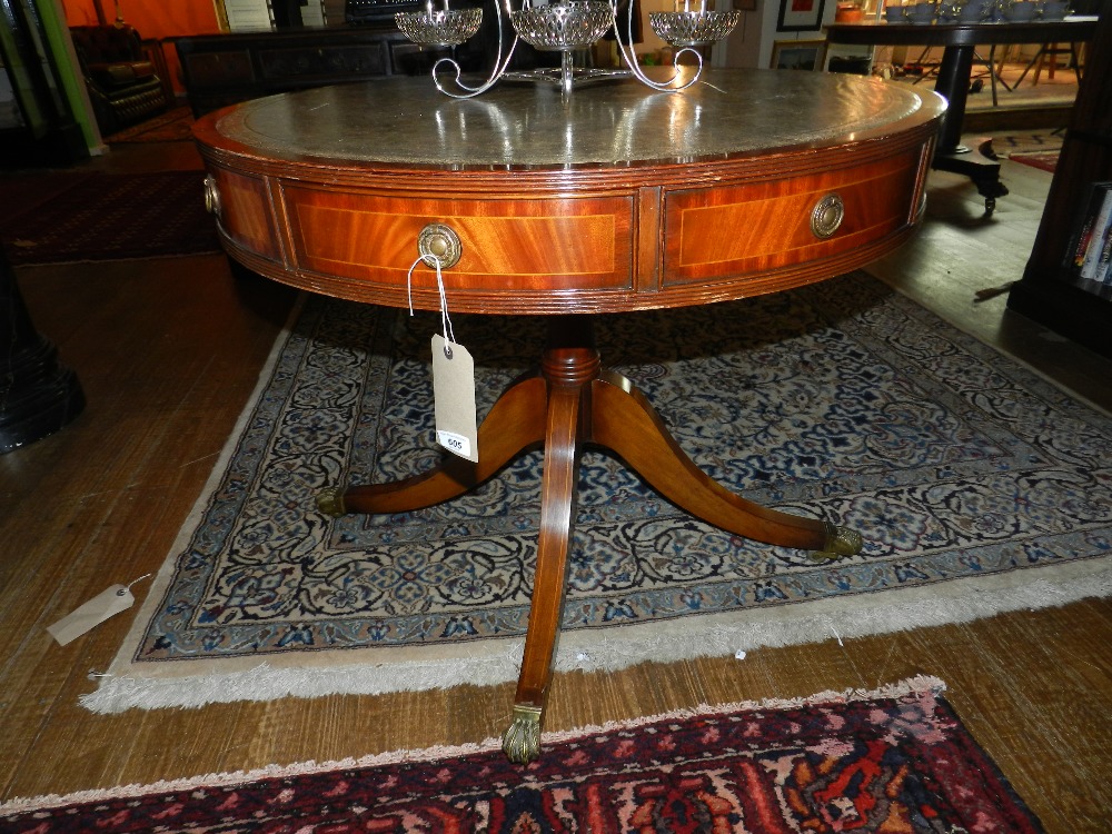 An inlaid mahogany pedestal drum table having tooled green leather insert above four drawers