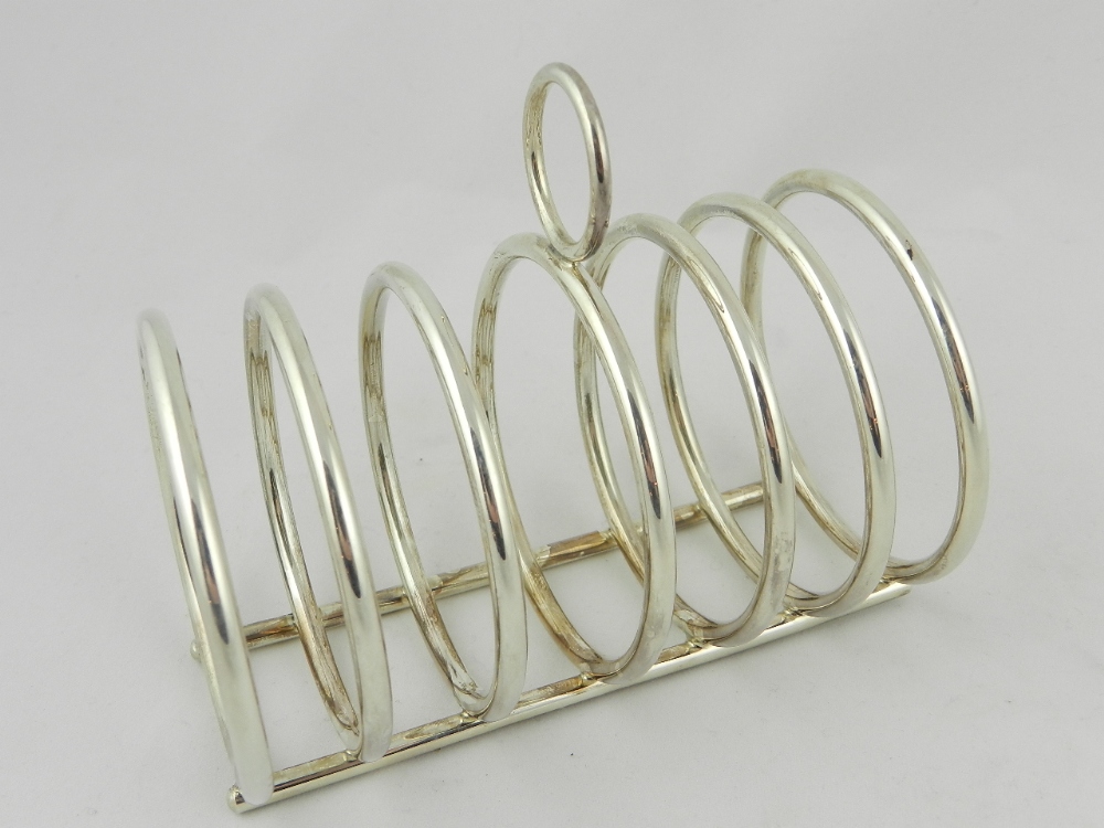 A silver toast rack, seven circular divisions with central loop handle