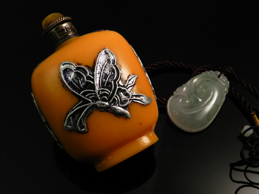 A snuff bottle decorated with white metal mounts along with a ceyldon green pendant.