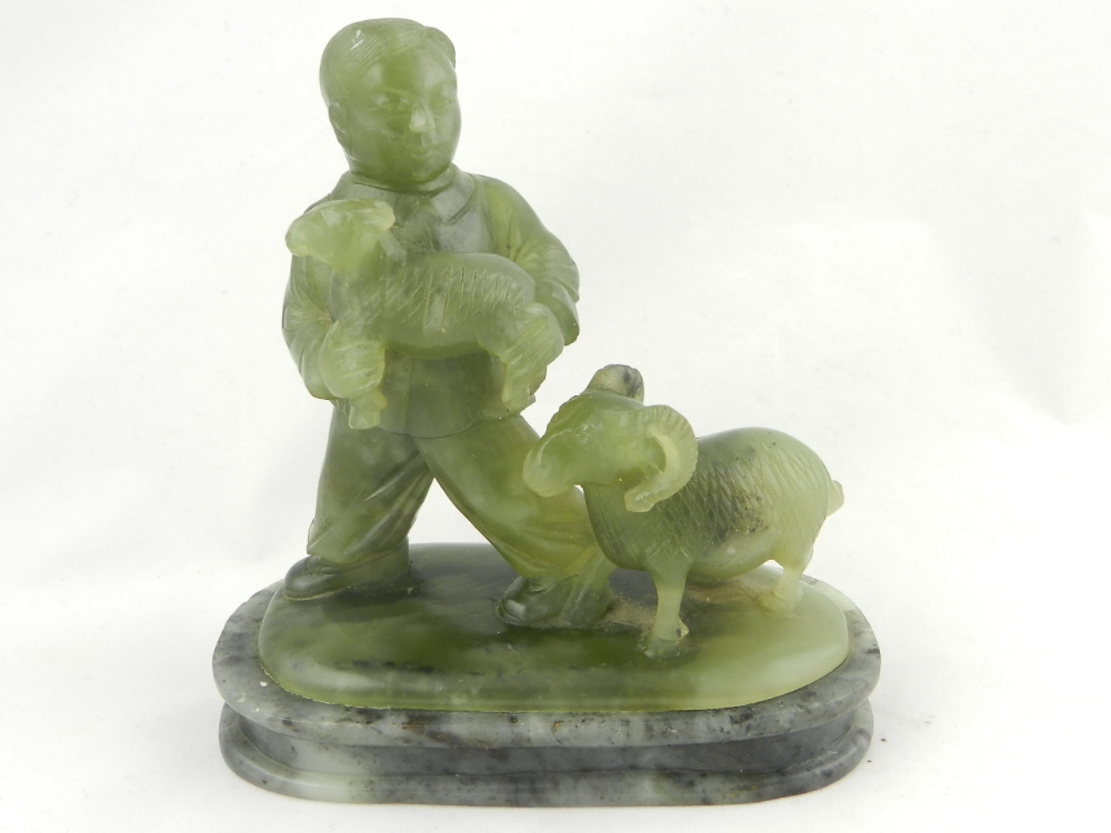A rare oriental green soapstone carving of a man carrying a lamp with a ram following.