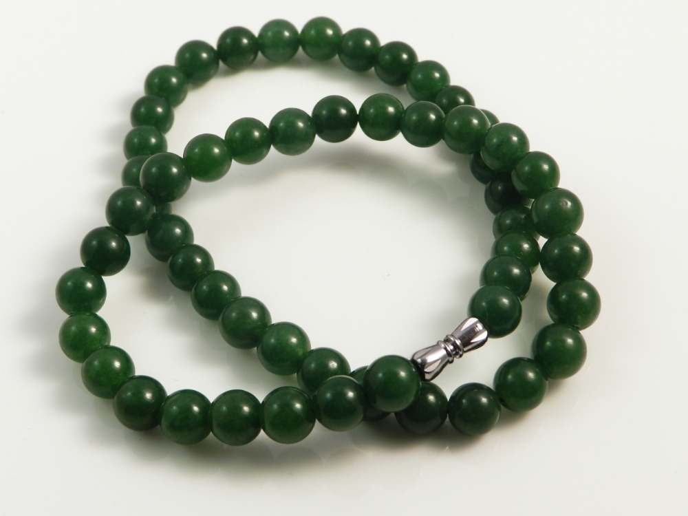 A green jade bead necklace having a white metal clasp.