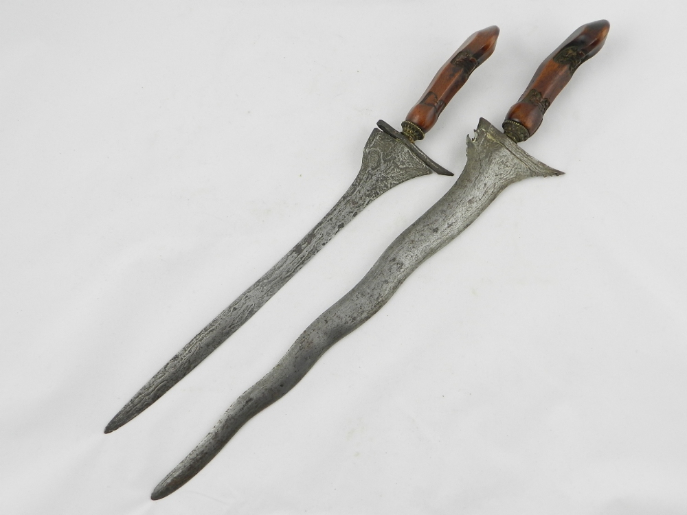 A pair of nineteenth century Kris daggers with decorative carved hardwood handles.