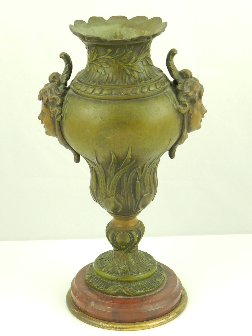 A bronzed spelter vase having maiden mask handles raised on a marble base.