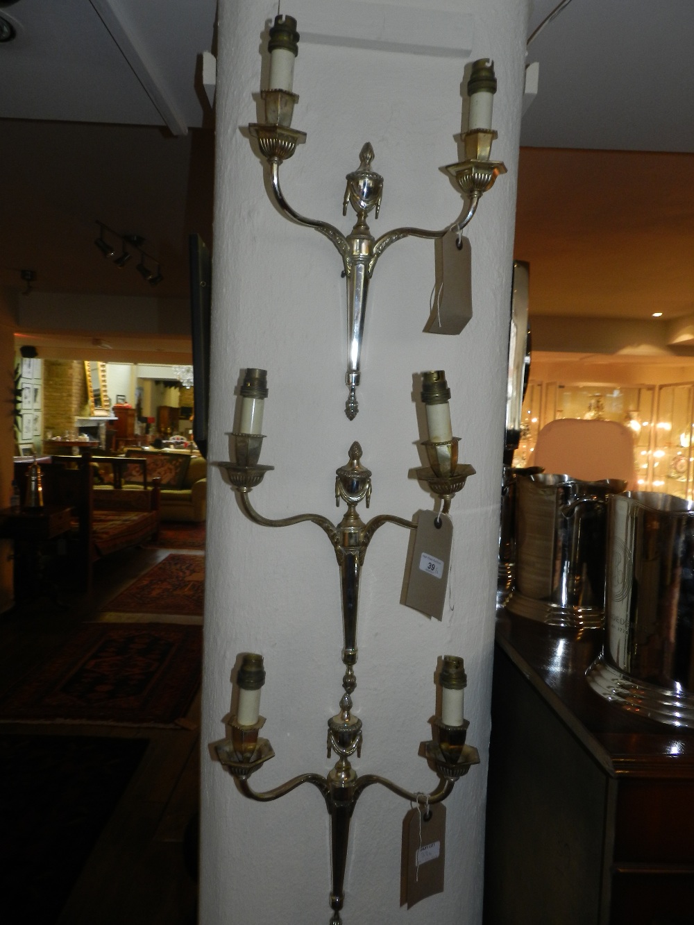 A set of three silver plated neo-classical twin light wall sconces decorated with draped swags and