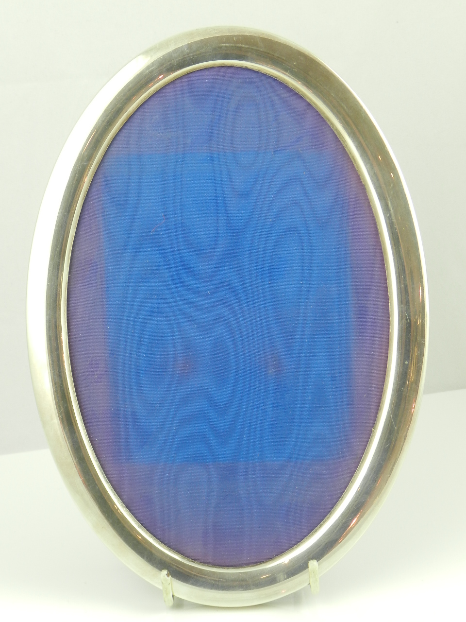 A large oval hall marked silver photo frame.