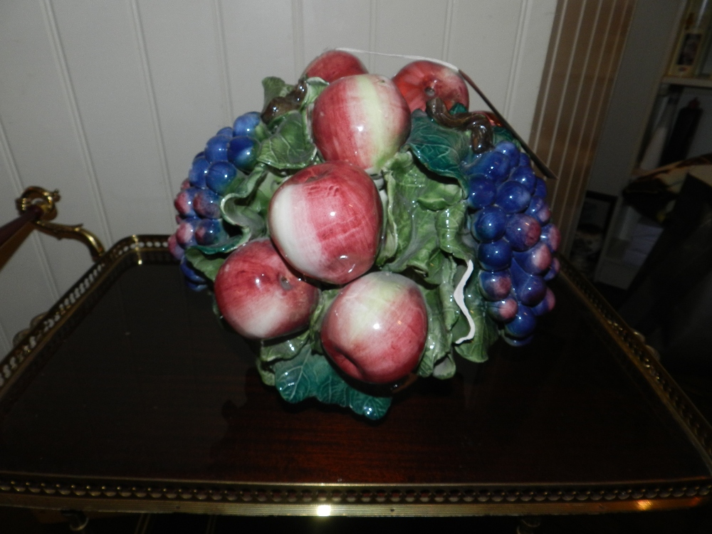 An Italian ceramic centre piece of  glazed apples and grapes in a bowl.