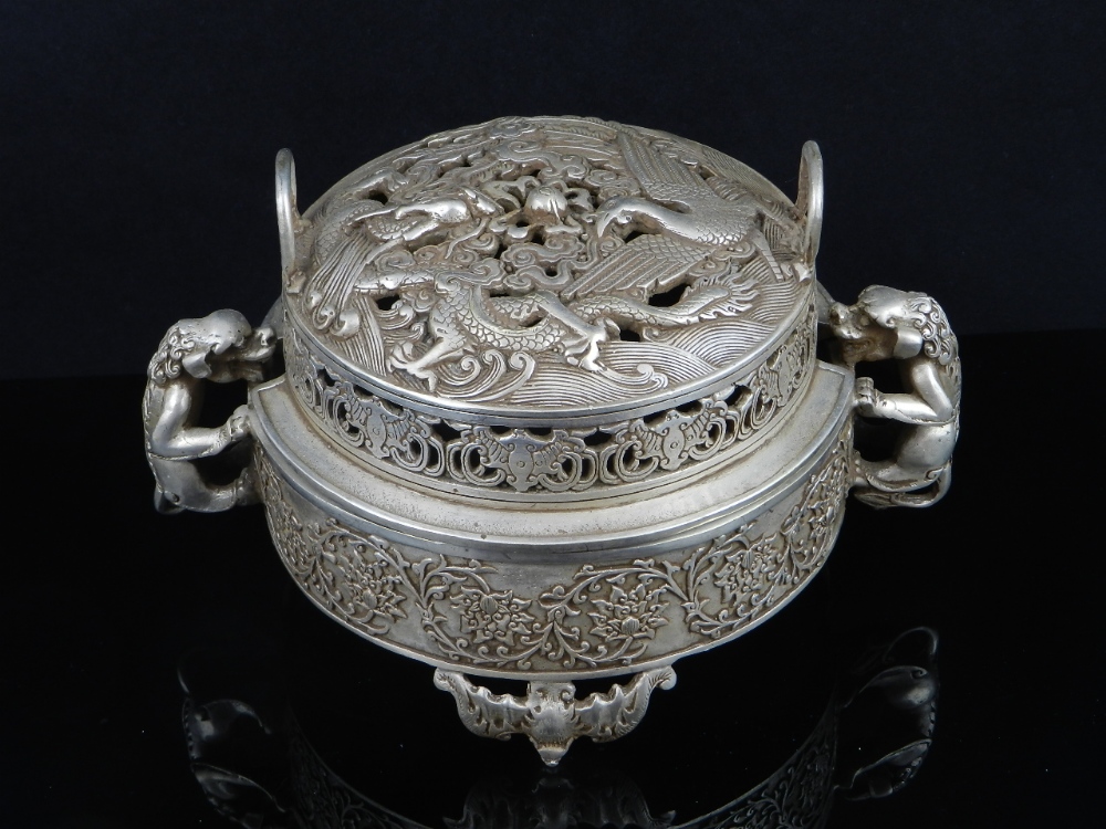 A Chinese white metal incense burner having pierced a dragon, a phoenix and a bat, decorated lid,