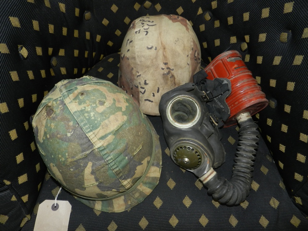 Two military camouflage helmets, one from the Vietnam period along with a 1941 gas mask.