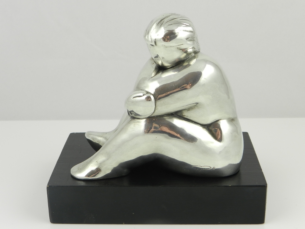 A white metal sculpture of a rotund seated woman stamped 925 and bearing signature raised on a