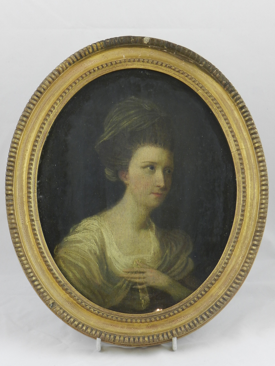 An 18th century oil on canvas portrait of a lady in a white dress, all in a gilt wood oval frame