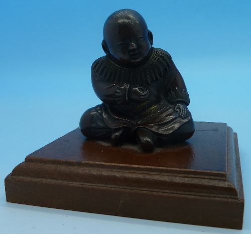 A small oriental bronze of a Buddha on a wooden plinth, height 7cms