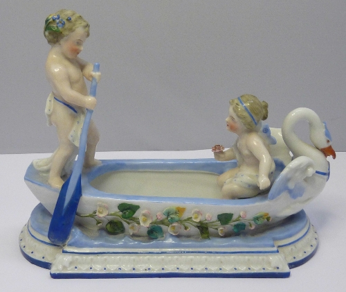 A KPM centrepiece in the form of two cherubs in a boat, length 19cms, height 15cms, a/f