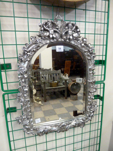 A silvered framed mirror surmounted by cherubs