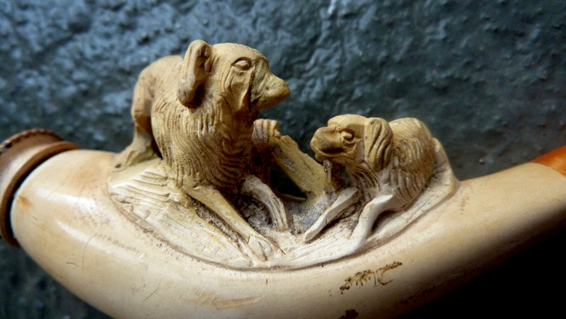 Two meerschaum pipes modelled with scenes of hunting dogs and terminating in amber mouthpieces 4½