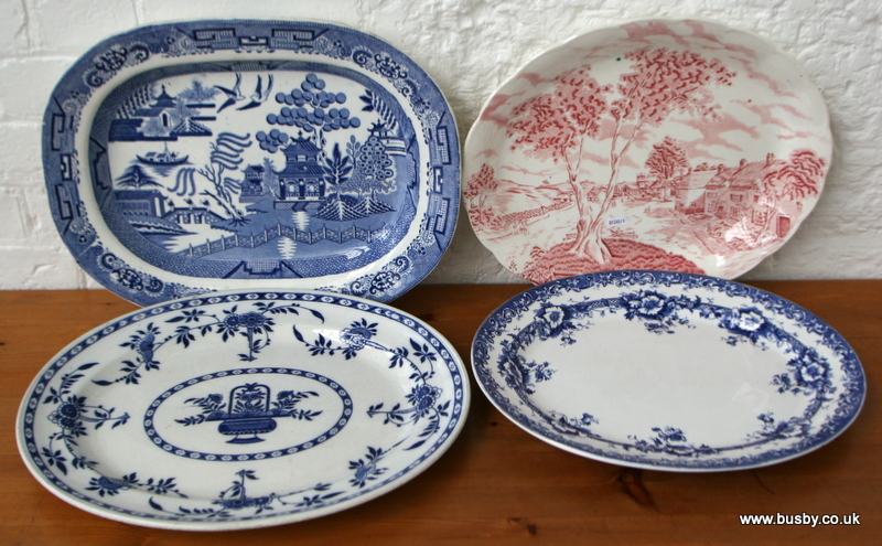 A willow pattern meat plate together with two blue and white, and one pink and white meat plates.