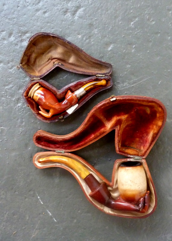 Two meerschaum pipes modelled as hands holding jars 6in(15cm)L and smaller.