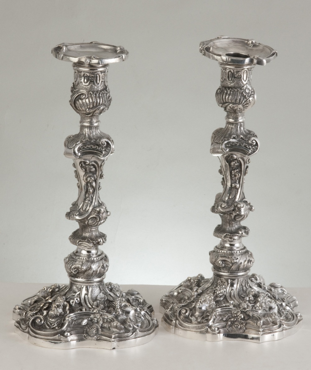 A pair of rococo revival electroplated silver candlesticks decorated with C-scrolls, rocaille, and