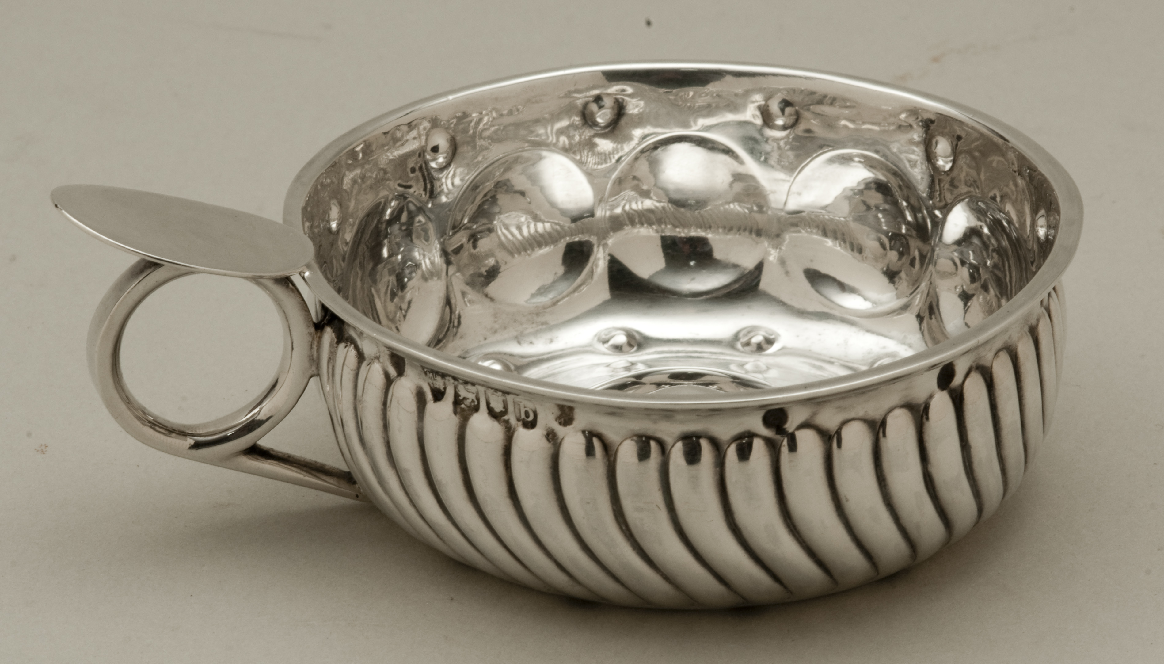 A late Victorian hallmarked silver tastevin with ribbed lobed sides and ring handle London 1897 by