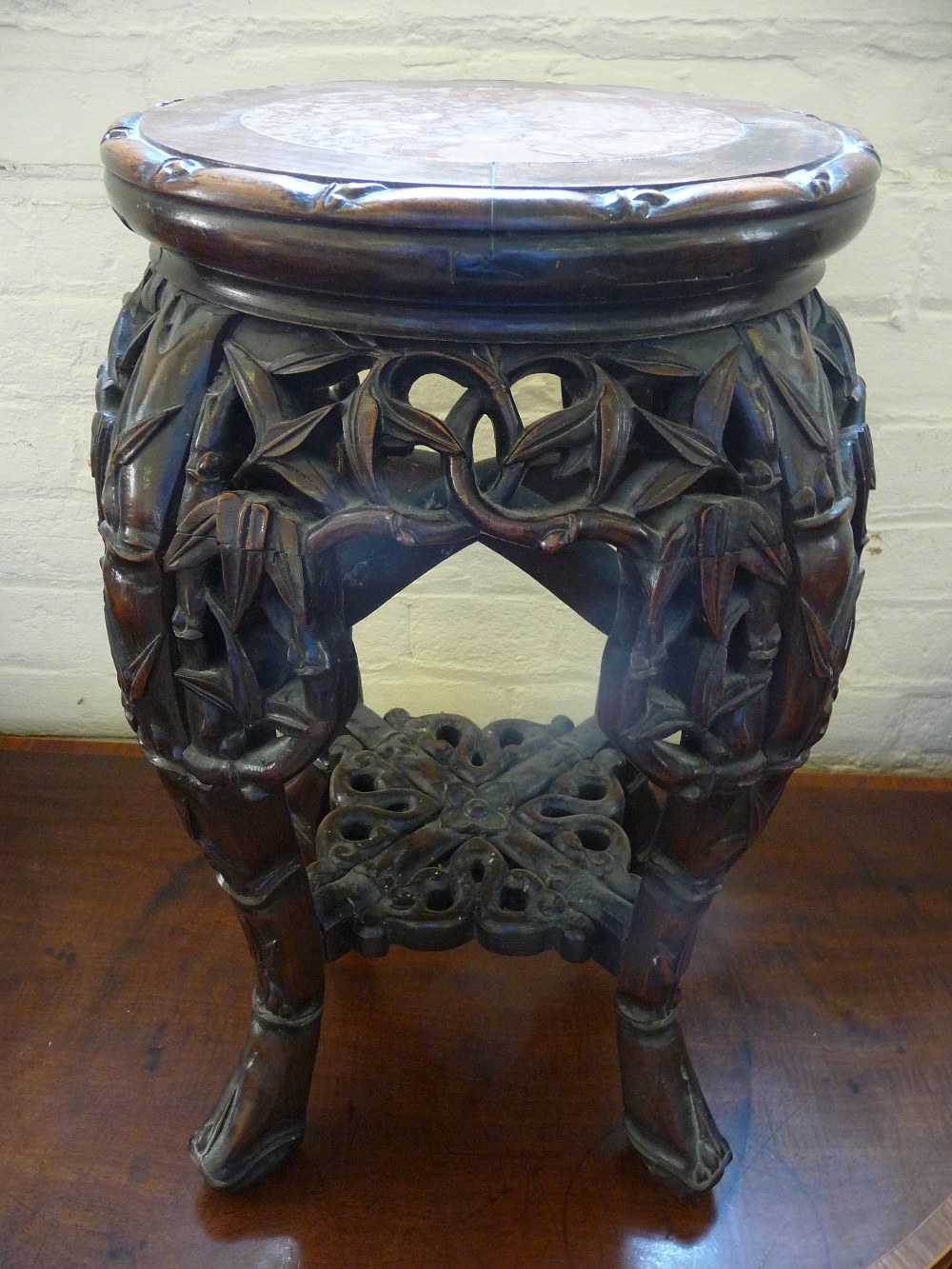 A profusely carved Eastern hard wood plant stand with inset marble top, dia 19", H. 19".