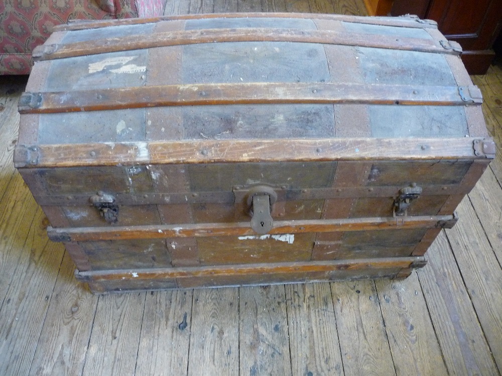 A domed topped wood and metal bound travelling trunk.