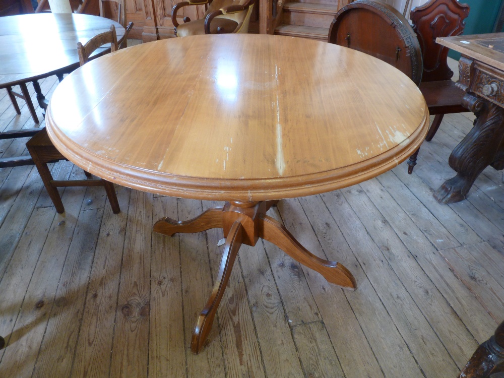 A glass topped circular Pine tripod table