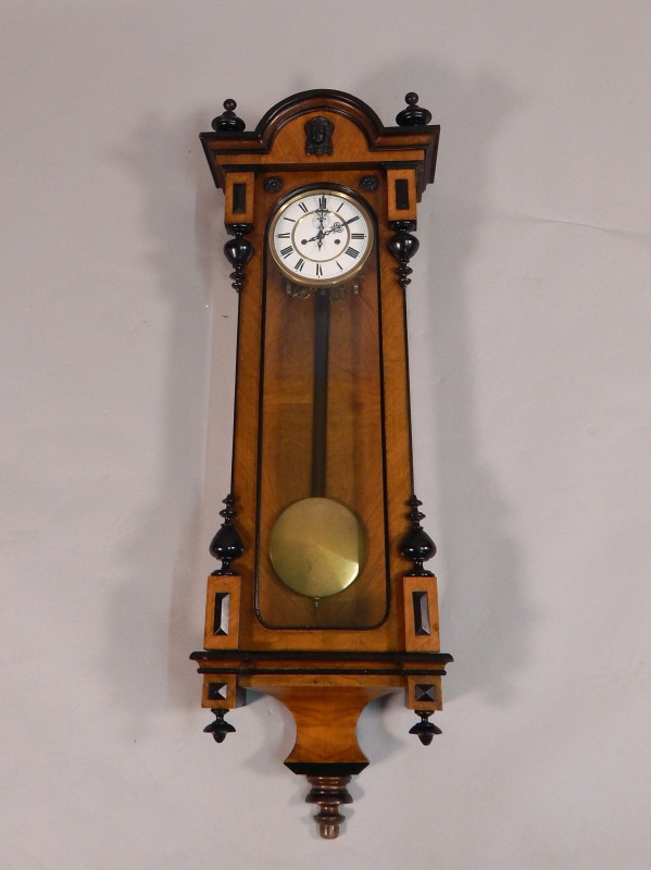 A Vienna type walnut and ebonised wall clock, the shaped top applied with a female mask, with a