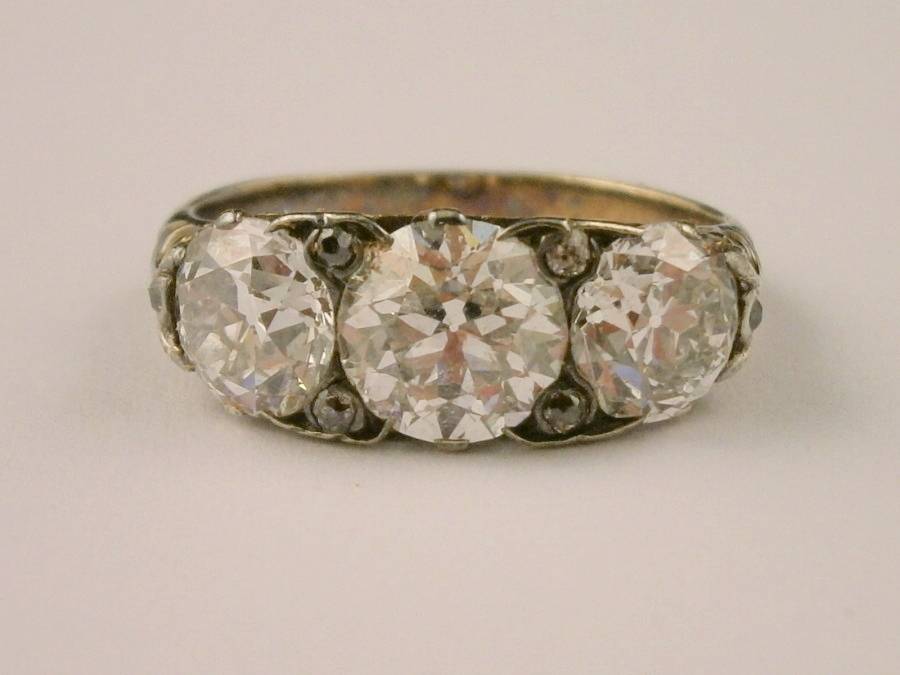 A three stone diamond ring, with three old English brilliant cut stones, of varying size, central