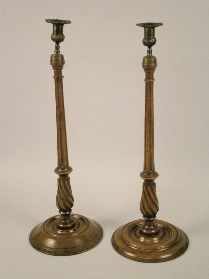 A pair of late 19th/early 20thC oak and brass candlesticks, each with a leaf cast sconce on a reeded