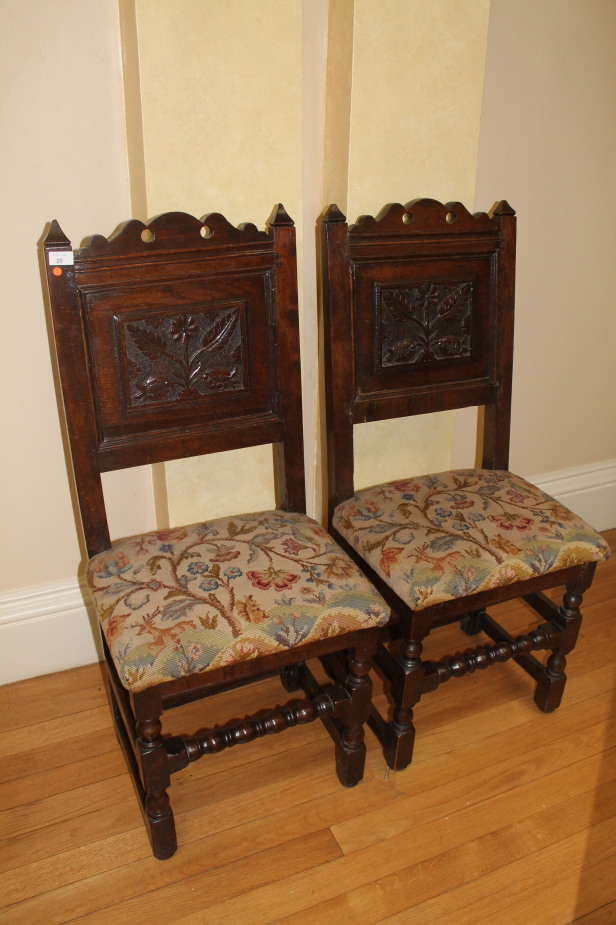 A pair of 17thC oak side chairs, with carved panel backs, over stuffed wool work seats and bobbin