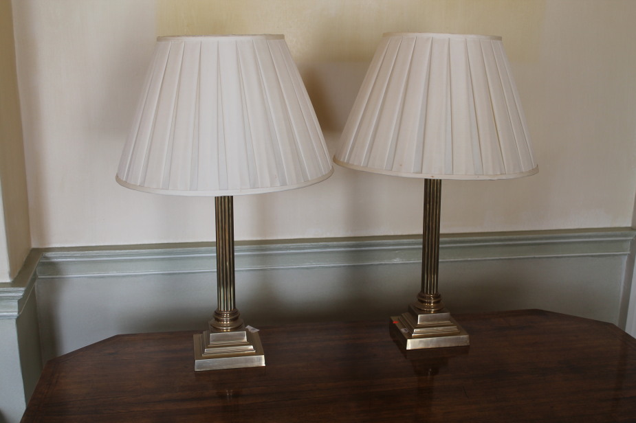 A pair of brass table lamps of Corinthian columnar form, with pleated shades, 70cm high.