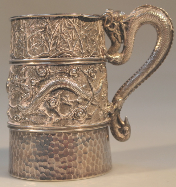 A late 19thC Chinese white metal tankard, repoussé decorated with dragons and bamboo, makers mark to