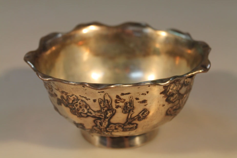 A Chinese white metal bowl, applied moulding`s of birds and cherry trees, with petalated rim, 6.5oz,