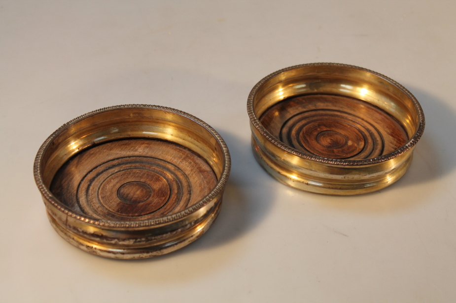 A pair of silver plated wine coasters, of typical form with gadrooned runes and turned wood bases,