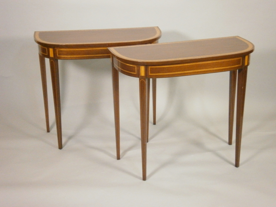 A pair of George III style mahogany demi-lune console tables, each with a satinwood cross banded