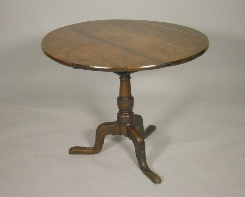 A George III oak tilt-top table, the circular top on a bird cage with turned column and tripod base,