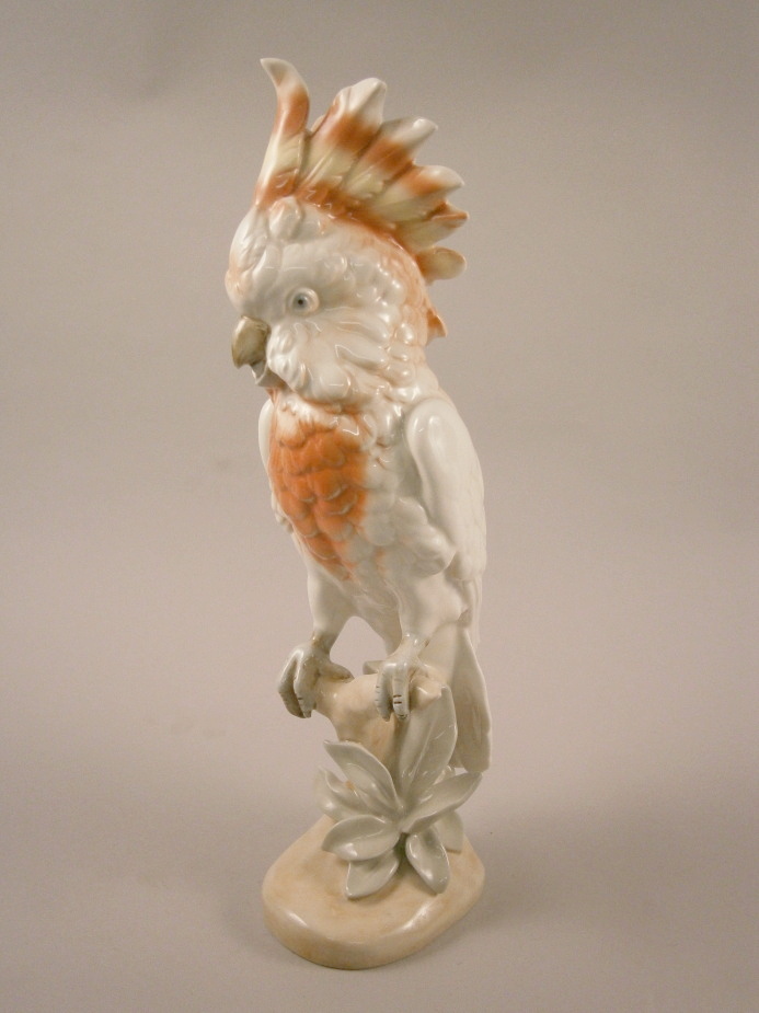 A Royal Dux porcelain Parakeet, modelled on a branch, picked out in red and yellow, various marks to