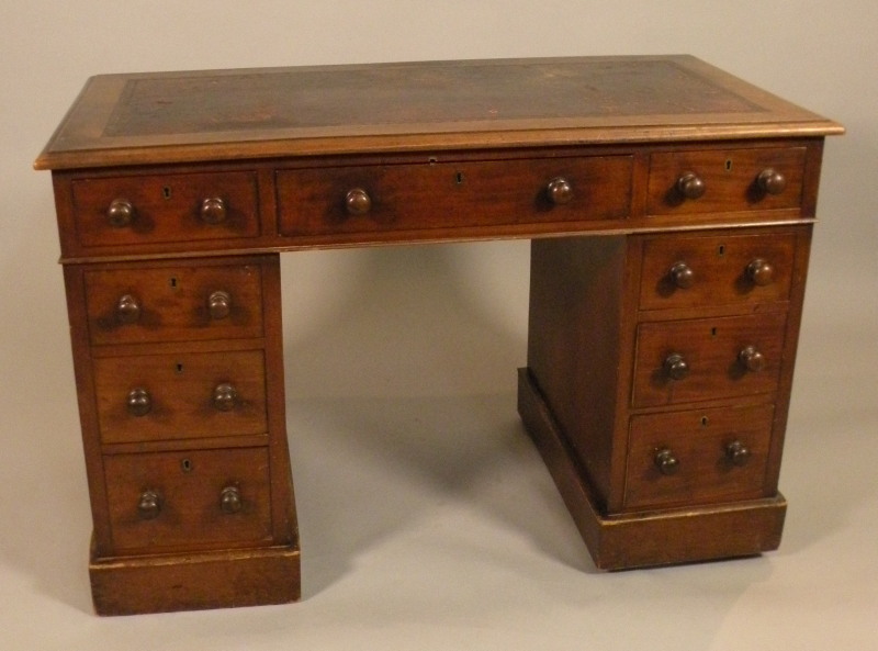 A Victorian mahogany pedestal desk, the top with a red leather inset with nine drawers on a plinth