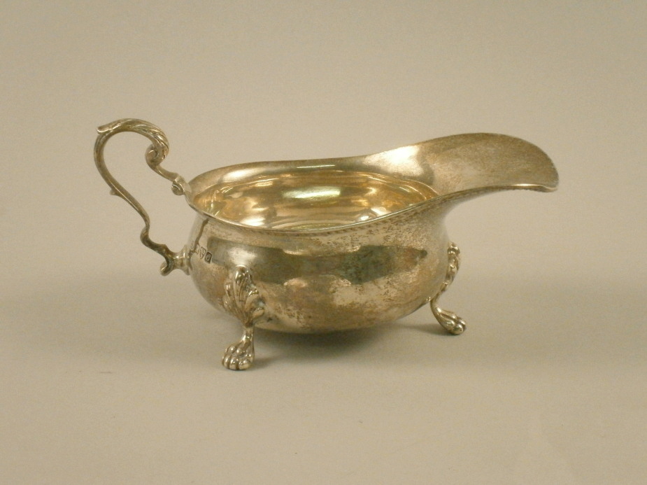 A silver sauce boat, with paw feet and scroll handle, Chester 1914, 9oz.