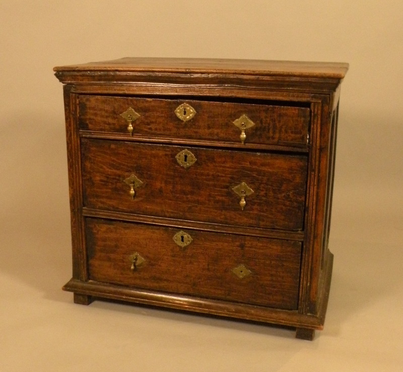 A 17thC and later oak chest, with a planked top above three drawers with later brass drop handles on