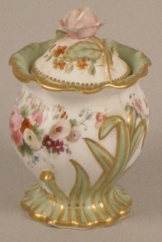 A 19thC Ridgway porcelain type small jar and cover, painted with flowers and with a rose encrusted