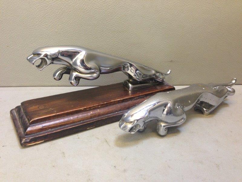 Two Jaguar car mascots, one on wooden presentation base.