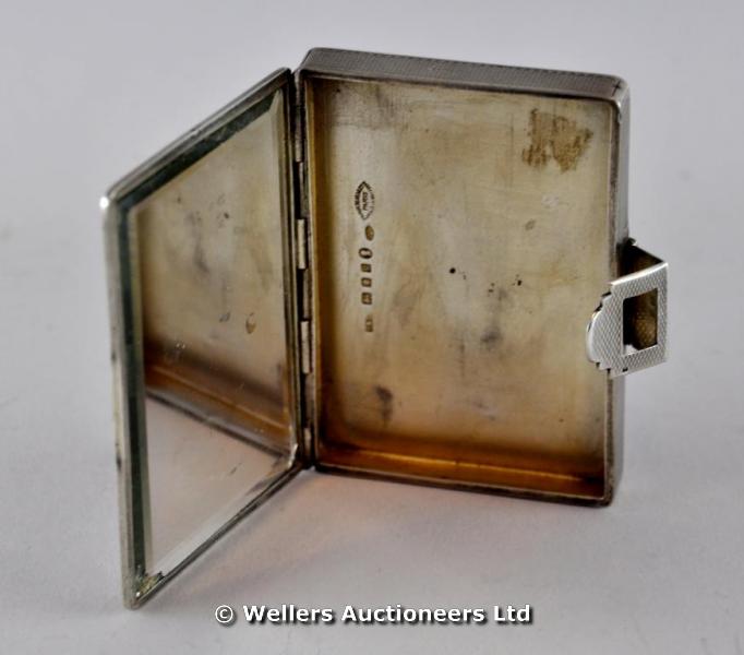 "An Art Deco silver box with onyx clasp, engine turned decoration and gilt interior with mirror,