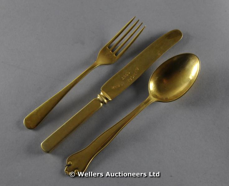 "A gilded white metal knife, fork and spoon, stamped AFRICAN MADE 1953 (3) "