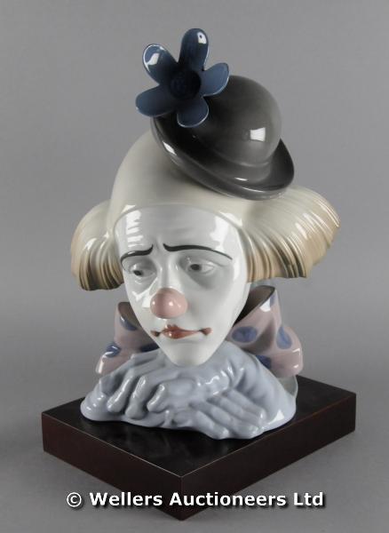 "A Lladro portrait bust of a clown with a sad face and a flower on his hat, with a separate wooden