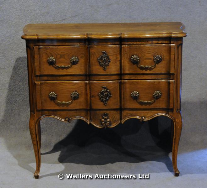 "A continental oak chest of two long drawers, with shaped top, bold brass handles and cabriole