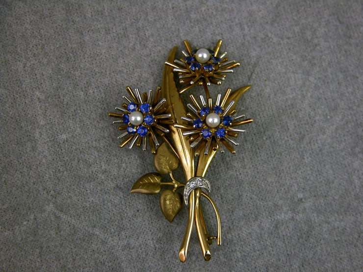 A 9CT GOLD FLOWER SPRAY BROOCH, each of the three flower heads set with six sapphires and a