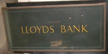 A Reclaimed Old ""Lloyds Bank"" sign, with gold lettering. In a metal frame 1075mm (42 1/2"") wide