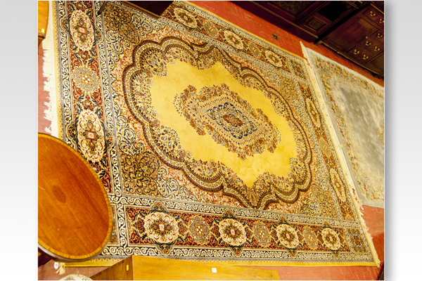 A mustard ground Keshan wool carpet having a wide floral crimson and blue border and with a centre