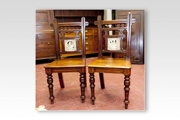 A pair of Edwardian mahogany hall chairs each with a bobbin back and a centre feature